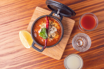 Traditional Mexican soup and tequila shots. Bowl spicy Mexican soup with a red chili garnish. Gourmet Mexican food