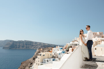 Fototapeta na wymiar Happy couple hugging and laughing together with a view of Santorini