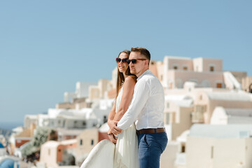 Fototapeta na wymiar Happy couple hugging and laughing together with a view of Santorini