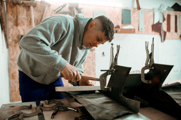 Professional tinsmith working with metal, workshop. Handmade, craftsmanship and blacksmithing concept - obrazy, fototapety, plakaty
