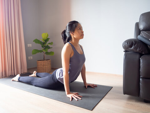 upward facing dog yoga pose asian woman home workout fitness body weight exercise pilates health training sport healthy lifestyle activity wellness care on mat indoors natural light selective focus - Powered by Adobe