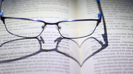 Ombre de lunettes en forme de cœur sur un livre