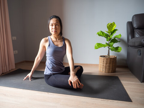 seated spinal twist pose yoga asian woman home workout fitness body weight exercise pilates health training sport healthy lifestyle activity wellness care on mat indoors natural light selective focus