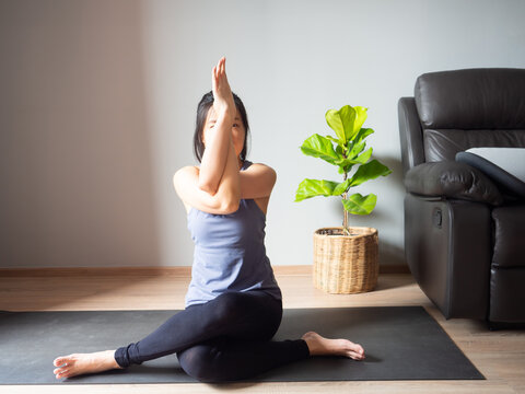 seated eagle pose yoga sitting Garudasana asian woman home workout fitness body exercise pilates health training healthy lifestyle activity wellness care on mat indoors natural light selective focus