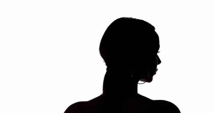 Female silhouette. Gender equality. Rights freedom. Dark contrast back view shape portrait of confused woman turning head looking at empty space isolated on white background.