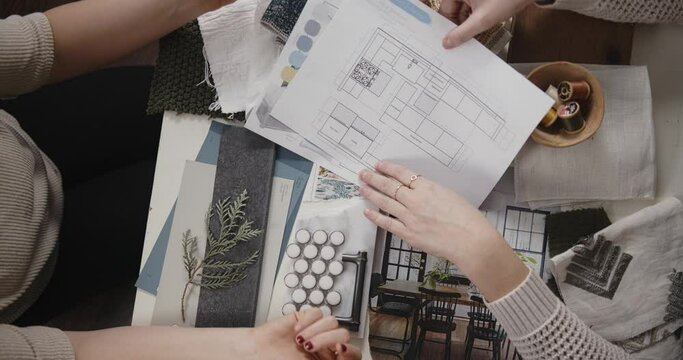 Two women working on interior design plans together, Top Down of Work Table