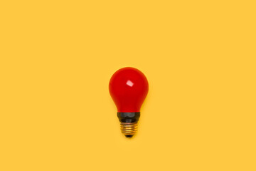 Bombilla de luz roja sobre un fondo amarillo liso y aislado. Vista superior. Copy space