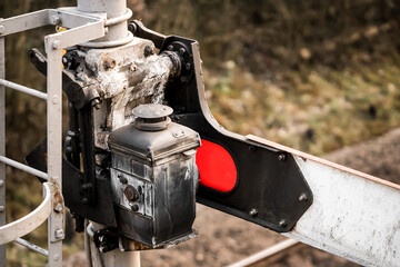 Old railway signal restored showing red stop light and lap behind mechanical gantry to light up...