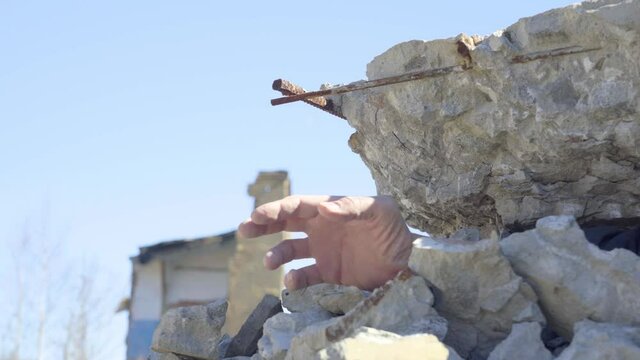 Males Hand Under the Rubble of Debris. The Victim, Littered with the Rubble of the Building, Calls for Help. Close-up. Daylight