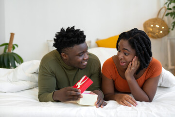 beautiful young african lie in bed with a gift 