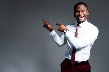 Happy african american businessman in shirt and tie points fingers to the side smiling. Place for inscriptions