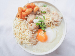 Top view of Rice porridge with minced pork, soft-boiled egg, sliced ginger and crispy noodle. 