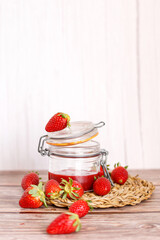 Strawberry jam in a jar on wooden background