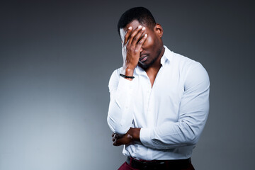 Tired African American man covers his face with his hand because of a headache. Fatigue during work