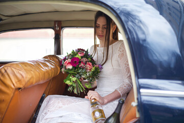 Braut zur Hochzeit mit Blumen im Auto