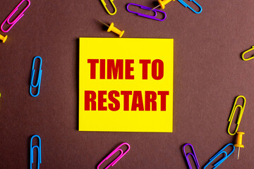 The words TIME TO RESTART is written in red on a yellow sticker on a brown background next to...