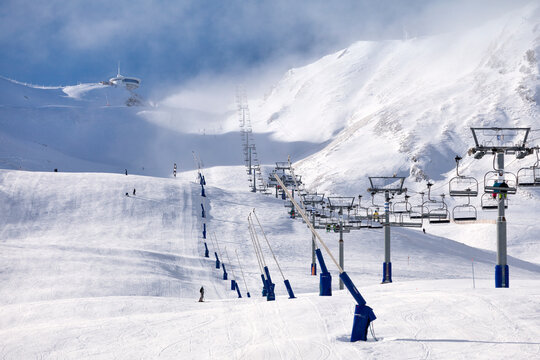 Nearly empty ski lift heading toward the top of the snow-capped mountain lost in the cloud in Pas de la Casa, Andorra