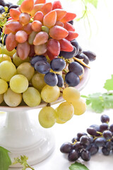 Colored grapes with leaves on a plate. Autumn harvest
