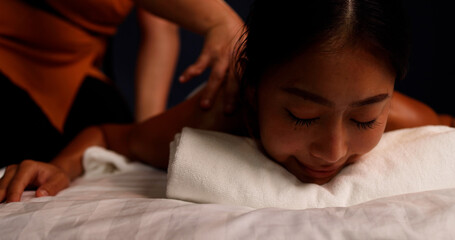Obraz na płótnie Canvas Young Asian woman receiving a shoulder massage at spa salon by professional masseuse, Spa treatment and thai massage concept