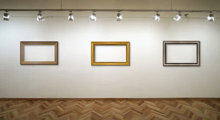 Interior of a white wall with frames and spot lights at art gallery