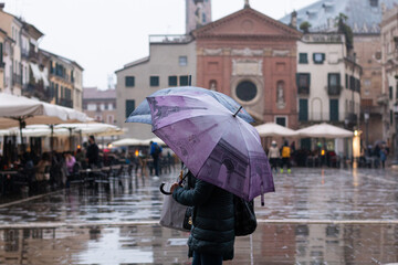 personas con paraguas de colores en dia lluvioso en plaza italiana antigua