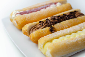 Mixed finger donuts filling chocolate, custard, jam and whipped cream, eclairs in different flavors