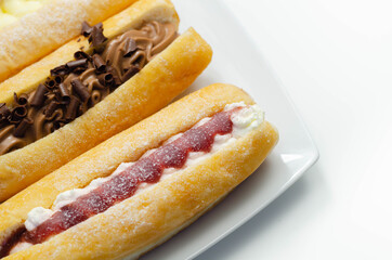 Mixed finger donuts filling chocolate, custard, jam and whipped cream, eclairs in different flavors