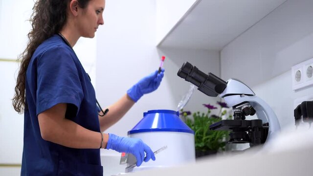 Veterinarian taking test tube out of hematology analyzer in laboratory