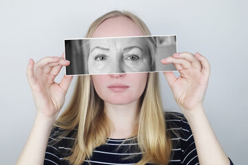 The girl holds a photograph of her old mother to her face. Aging, genetics, family tree and loss of youth concept. Before and after age-related changes.