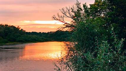 Fototapeta na wymiar Beautiful blazing sunset landscape above river and orange sky in evening