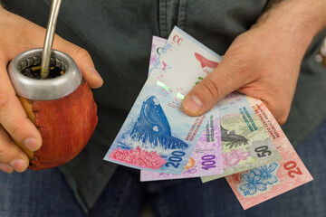The man is holding Yerba mate and Argentinian money. Business and financial concept, Symbol of...