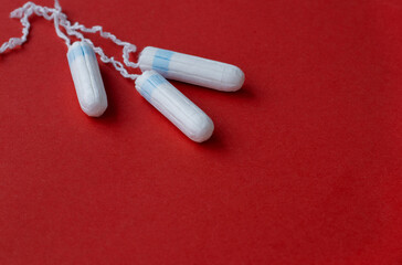 three female tampons lie on a bright red background. Feminine hygiene products. Copy space. High quality photo