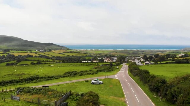 Backwards Moving Shot From The Road Leading Into Llangennith Village, With Rhossili Beach and Rhossili Bay In The Background, In The Gower Peninsula, Llangennith, Wales