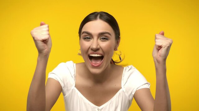 Excited woman showing yes gesture isolated on yellow