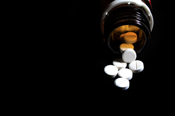 Medicine prescription on black background. Open bottle white medicine pill spilling out isolated on black background. Open pill bottle with medicine (medical and health care related)