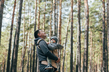 Dad carrying his 1 years old son in ergo carrier. Authentic moment. Concept of leisure outdoor