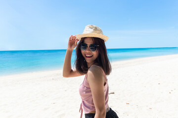 Face of young woman wearing pink tank  straw hat wearing sunglasses. Happy woman smiling during summer vacation at sea. Beautiful lady relaxing at beach. fresh sky. Holiday, tropical, comfortable