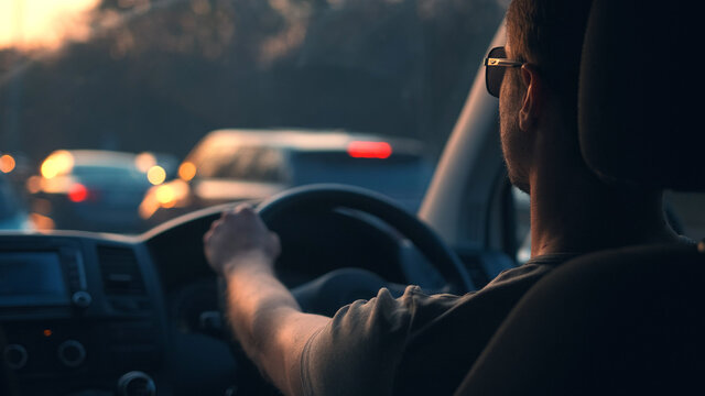 The young man driving the car along the city highway