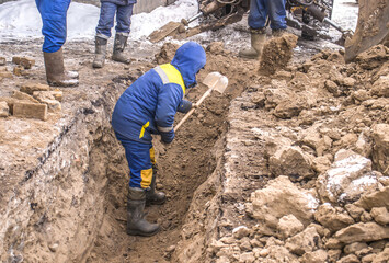 Digging trenches in winter in the city by hand with a shovel.