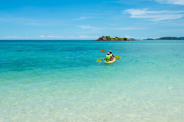 Family backward view playing Kayak or canoeing in the sea. Family People traveler kayaking in the ocean. Holiday and outdoor concept. Fresh water. Family time concept. Clear nature. Copy space.