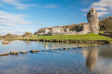Fototapeta na wymiar Ogmore Castle, A ruined Norman castle near Bridgend, south Wales. The castle is reflected on the smooth water of the river Ogmore.