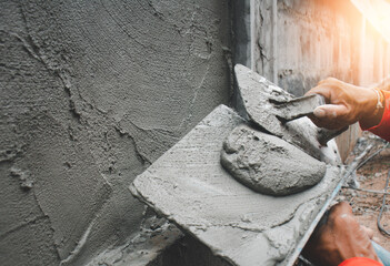 Construction workers in industrial buildings are plastering to build walls.