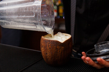 Bartender finishes preparation of exotic alcoholic cocktail in coconut