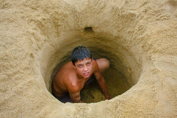 Homem num buraco na areia com seu rosto.