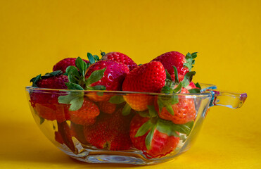 strawberries in a vase on a yellow background side view