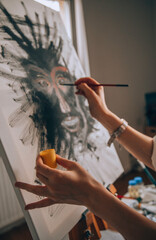 Beautiful talented female artist painting at her home.