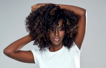 Sexy black woman playing with her afro hair isolated on gray background