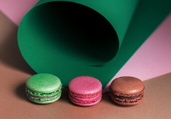 French macaroons on a multi-colored paper background with place for text. Pastry chef app with copy space. Creative concept.