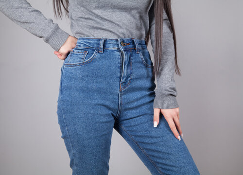Young beautiful woman wearing blue jeans. Gray background.