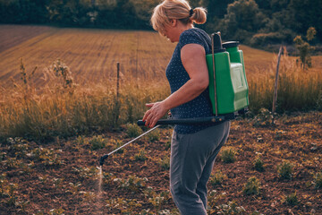 Woman gardening her garden. Spraying pesticide. © Kitja